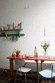 Wooden table, bench and chairs on veranda with white brick wall