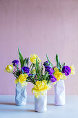 Spring flowers in three vases shaped like crushed tin cans