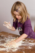 A little girl kneading dough