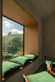 Green armchairs and matching cushions on window sill in panoramic window with view of landscape