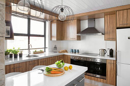 Gemüse auf der Kücheninsel in moderner Küche mit Holzfronten