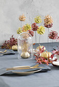 Table set in autumnal style with painted pumpkins and pine cones