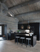 Modern, open-plan kitchen with black cabinets in grey log cabin
