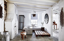 Walled-up fireplace, day bed, pallet, chest and stool in a rustic living room