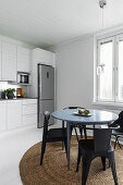 Round table and chairs on round rug next to white kitchen counter