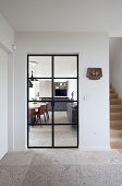 Blick vom Flur mit Steinboden durch eine Glastür in die Wohnküche