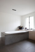 Bathtub clad with stone panels below window