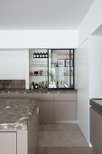 Kitchen shelves with open sliding glass door and base cabinet with marble worksurfaces
