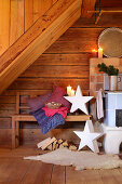 Arrangement of candles and stars in rustic wooden cabin with bench next to log burner