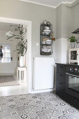 Cement floor tiles in kitchen with wire shelving above radiator