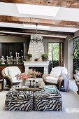 Rattan armchairs and ottoman with animal print in front of fireplace on living terrace
