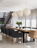Upholstered chairs and spherical lamps in elegant dining area with glass wall