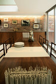 Two-tone table in dining room with fitted wooden sideboard and brick wall