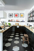 U-shaped fitted kitchen with black base cabinets and wooden worksurface