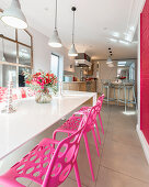Hot-pink chairs at dining table in sunny kitchen-dining room