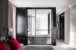 Blick vom Schlafzimmer durch Glastür ins Badezimmer mit Designerbadewanne