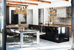Black granite kitchen island, dining table and classic chairs in open living space
