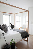 Himmelbett in elegantem Schlafzimmer, im Hintergrund Armlehnstuhl und Einbauschrank