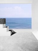 Pouf with black and white cover and bikini on terrace with sea view