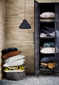 Stack of pillows next to black cupboard with home textiles