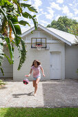 Girl plays with basketball on forecourt