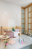 Bed and balance bike in child's bedroom in pastel shades