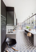 Long, narrow kitchen with concrete counter, cement tiles and glass wall
