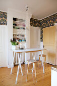 High table and bar stools in front of shelves of crockery in kitchen with wooden floor