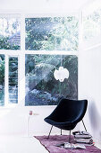 Black designer armchair and books by the window to the garden