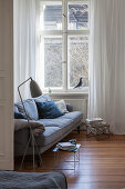 Sofa und kleine Beistelltische vorm Fenster im Altbau