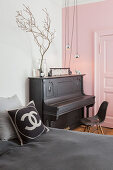 Klavier vor rosafarbener Wand und Kassettentür im Schlafzimmer
