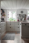Panelled cabinets and wooden floor in pale country-house kitchen