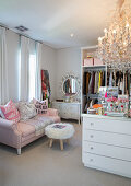 Feminines Ankleidezimmer mit rosa Sofa, Fellhocker, Schminktisch und Kronleuchter