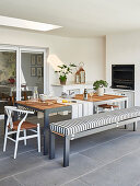 Dining table with bench and chairs in front of fireplace on furnished terrace