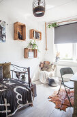 Hanging chair, old wine crates used as shelving modules and metal bed in teenager's bedroom