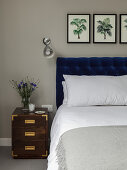 Double bed with deep-blue headboard, wall-mounted lamp and bedside cabinet in bedroom