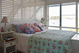 Floral textiles and glass wall in romantic, shabby-chic bedroom
