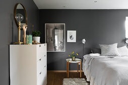 Double bed and white chest of drawers in bedroom with dark grey walls