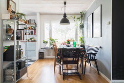 Dining area with grey wall and parquet floor in open-plan kitchen with metal shelves in foreground