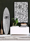 Paddle, surfboard and lowboard on wheels with modern art on top