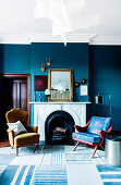 Two armchairs in front of the open fireplace in the living room with blue walls