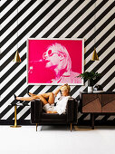 Fotografie im Pink an schwarz-weiß gestreifter Wand, blonde Frau in braunem Sessel