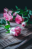 Rosa Rosen auf rustikalem Holztisch