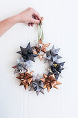 Hand holding Christmas wreath of origami stars