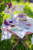 Table set with muffins, tea and lilac in garden
