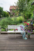 Cherries, cushions and crocheted blanket on white bench on terrace