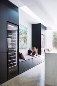 Girl sits on the bench in modern black kitchen