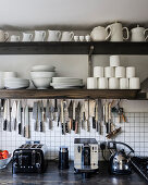Offenes Regal mit weißem Geschirr über Küchenarbeitsplatte mit Messerhalter, Toaster und Wasserkocher