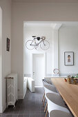 Bicycle hung on wall in hallway and open-plan dining area in period building