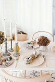 Autumnal arrangement of hydrangeas and candlesticks on table